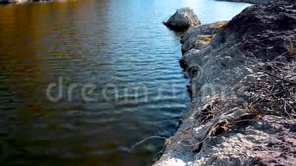 肮脏的水平静地流在岩石上而沙海岸顶的角度视频的预览图