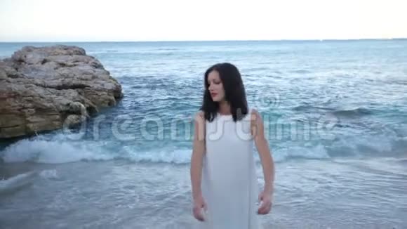 穿着白色连衣裙的漂亮女孩正在海边休息慢动作希腊视频的预览图