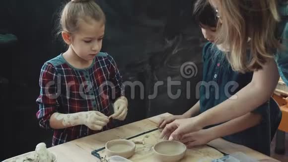 与粘土一起工作的车间妈妈带着两个小女儿正忙着用粘土做模特家长和家长的共同创造力视频的预览图