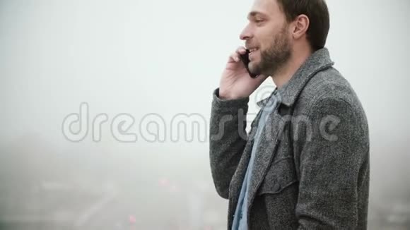 年轻英俊的男子站在法国巴黎埃菲尔铁塔附近在雾蒙蒙的早晨用手机交谈视频的预览图