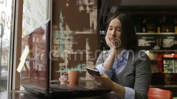 可怜的女人在舒适的咖啡馆里用智能手机视频的预览图