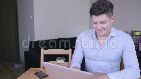 快乐微笑的年轻人在家里工作和在笔记本电脑上打字视频的预览图