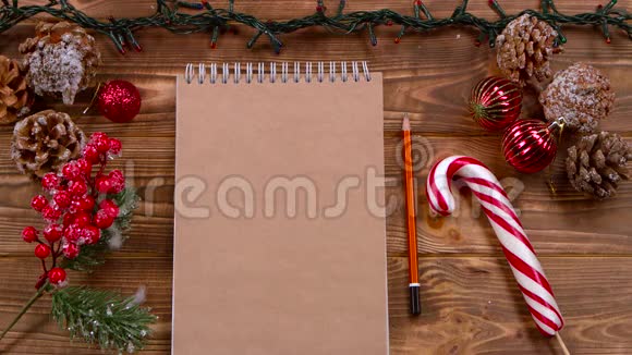 口袋笔记本和铅笔躺在桌子上圣诞玩具和花环周围顶部视图视频的预览图