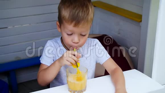 肖像一个四岁的男孩用果汁破坏让气泡通过吸管变成果汁制造灯泡飞溅他是视频的预览图