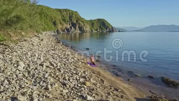 沙滩瑜伽与绿山相映的无人机动作接近女孩视频的预览图