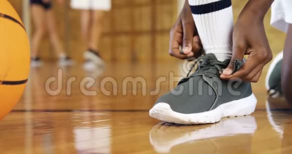 在篮球场系鞋带的高中生视频的预览图