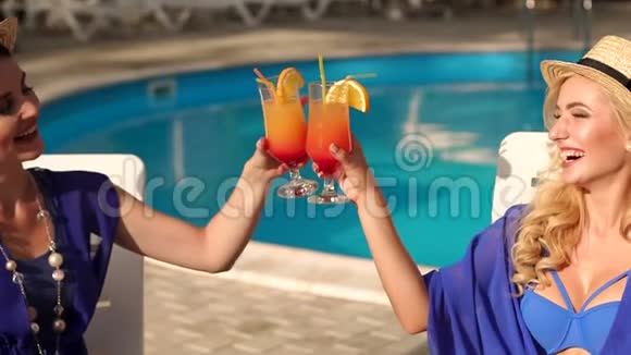 两个女孩在泳池边喝杯鸡尾酒视频的预览图