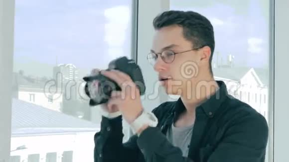 英俊的摄影师用专业相机在全景窗口附近拍照显示了他对全景的满意程度视频的预览图