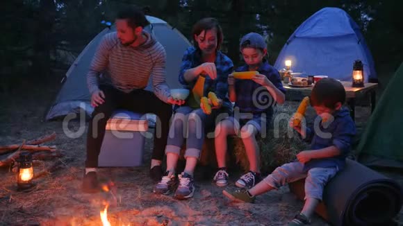 美国家庭吃盐玉米旅游野营森林野餐妈妈爸爸和儿子吃新鲜的黄色玉米视频的预览图