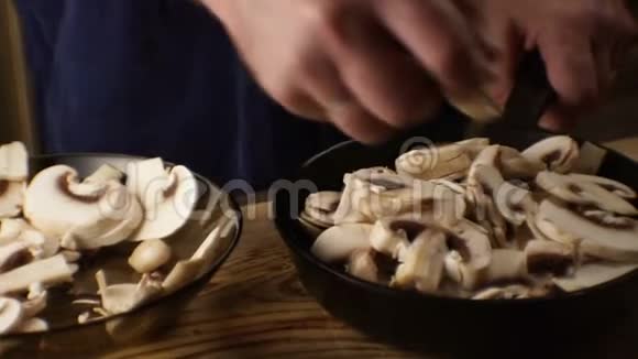男人把蘑菇从盘子里移到煎锅里视频视频的预览图