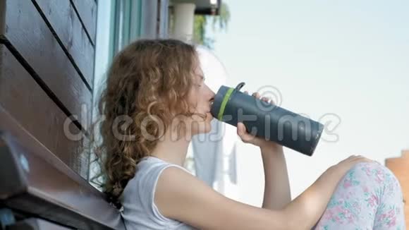 运动的女人在公园里慢动作地喝一瓶水视频的预览图