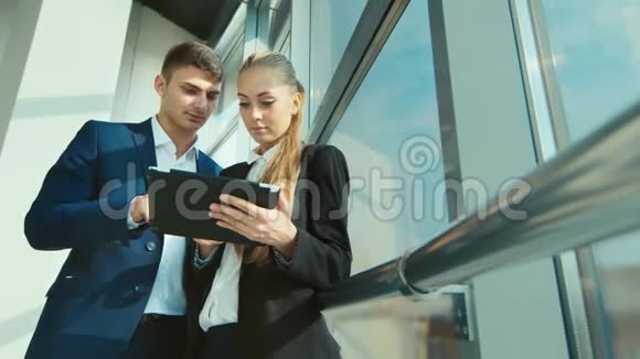两个年轻的商人在办公室里交流生意在一扇大窗户的背景下视频的预览图