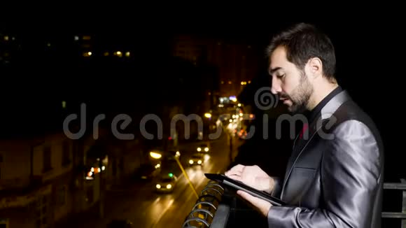年轻的商人在阳台上穿着正式西装使用平板电脑视频的预览图