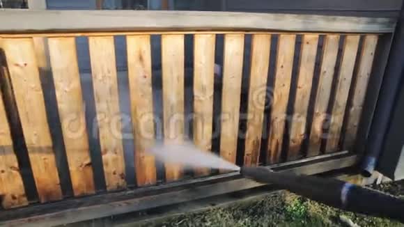 带有动力洗衣机的人清洁露台木制露台栏杆上的高压水清洁器视频的预览图