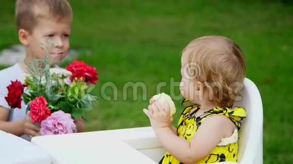 夏天在花园里这个四岁的男孩把一束花送给他一岁的妹妹弟弟视频的预览图