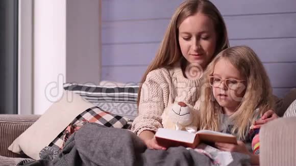 妈妈和女儿在沙发上读睡前故事视频的预览图