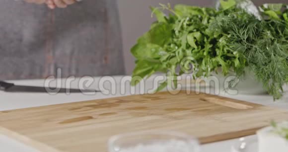 一个穿着围裙的女人把湿红樱桃西红柿的手扔在白色的准备沙拉的木板上视频的预览图