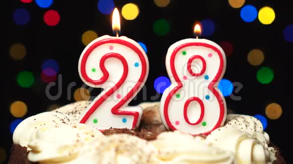 28号在蛋糕上面28号生日蜡烛燃烧在最后吹出来彩色模糊背景视频的预览图
