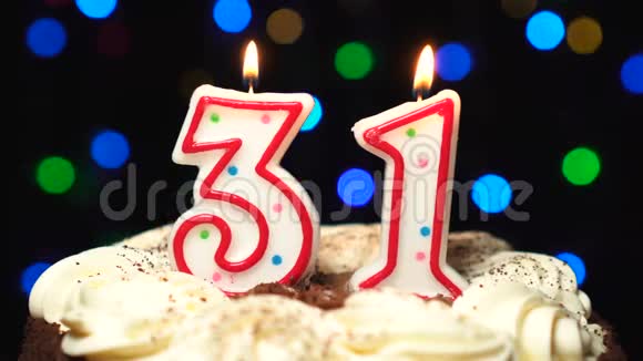 在蛋糕上面的31号三十一岁生日蜡烛燃烧在最后吹灭彩色模糊背景视频的预览图