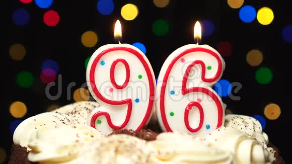 数字96在蛋糕上面96岁生日蜡烛燃烧吹灭在最后彩色模糊背景视频的预览图