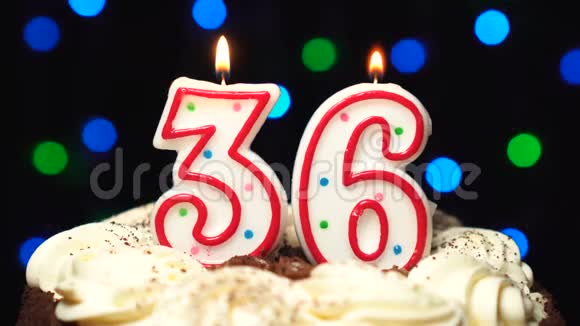 在蛋糕上的36号三十六岁生日蜡烛燃烧在最后吹彩色模糊背景视频的预览图