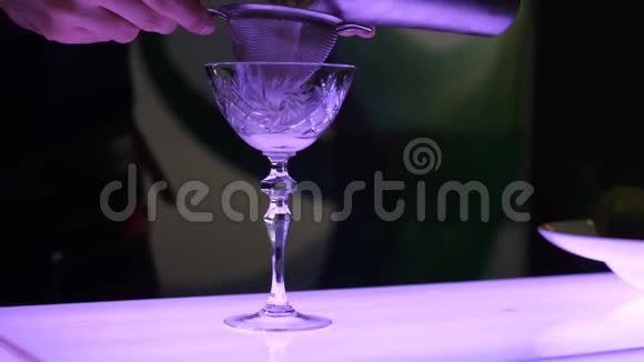 鸡尾酒的制作过程中酒保在一个漂亮的杯子里用长腿过滤掉鸡尾酒鸡尾酒视频的预览图