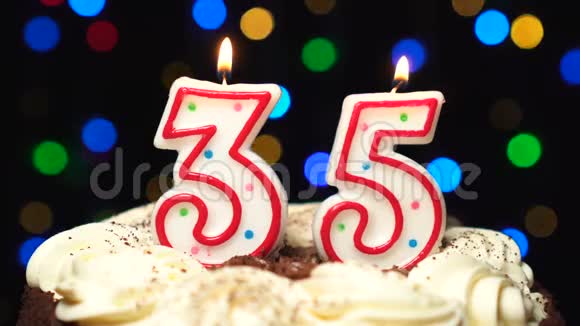 在蛋糕上面的35号三十五岁生日蜡烛燃烧在最后吹灭彩色模糊背景视频的预览图