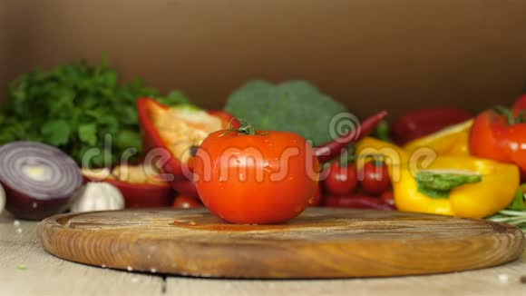 鲜辣的红番茄上面有流动的水滴特写放在一块木板上上的木板上红辣椒视频的预览图