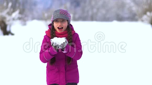 雪中田野里美丽的小女孩从手心吹雪视频的预览图