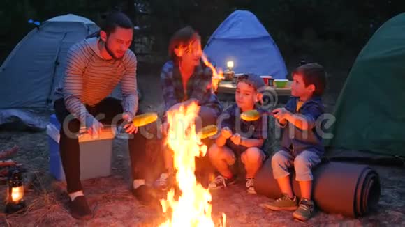 在森林里野餐美国一家人围着火在晚上准备黄色玉米母亲孩子和父亲在夏天视频的预览图