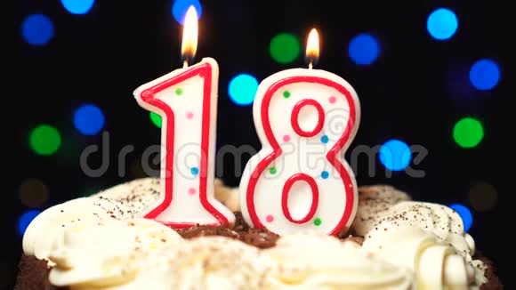 在蛋糕上面的18号18岁生日蜡烛燃烧在最后吹出来彩色模糊背景视频的预览图