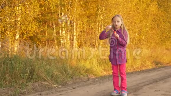 快乐的年轻白种人女孩在户外吹肥皂泡金秋树背景视频的预览图