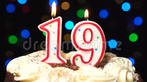 在蛋糕上面的19号19岁生日蜡烛燃烧在最后吹灭彩色模糊背景视频的预览图
