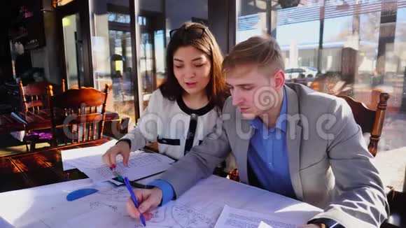 男孩在咖啡桌上帮助女朋友完成建筑师的家庭任务视频的预览图