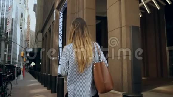 年轻女商人穿过美国纽约金融区走向办公室的背景慢动作视频的预览图