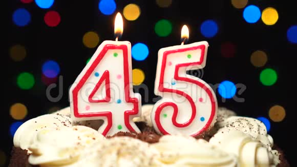 在蛋糕上面的45号45岁生日蜡烛燃烧在最后吹灭彩色模糊背景视频的预览图