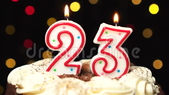 在蛋糕上的23号二十三岁生日蜡烛燃烧在最后吹灭彩色模糊背景视频的预览图