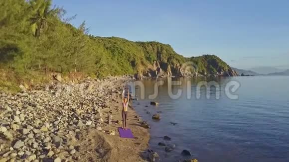 在海边的沙滩上练习瑜伽姿势的女孩视频的预览图