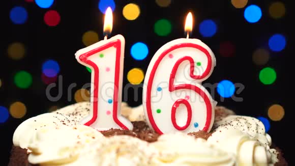 在蛋糕上面的16号16岁生日蜡烛燃烧在最后吹灭彩色模糊背景视频的预览图