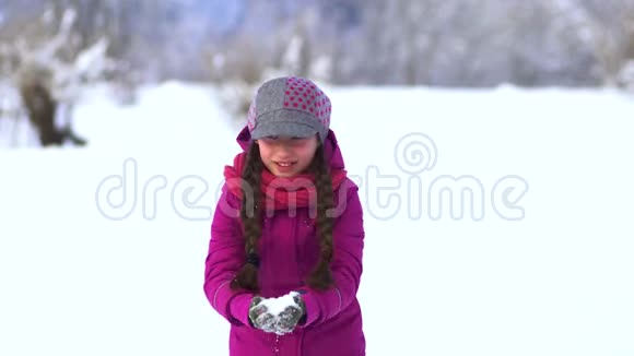 雪中田野里美丽的小女孩从手心吹雪视频的预览图