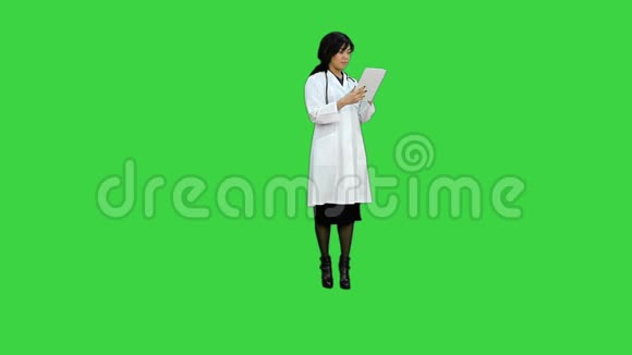 外科女医生用平板电脑微笑用绿色屏幕上的照相机交谈Chroma键视频的预览图
