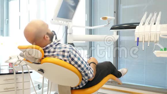 一位男性病人坐在牙医椅上的录像他转过身来微笑成镜头竖起大拇指视频的预览图