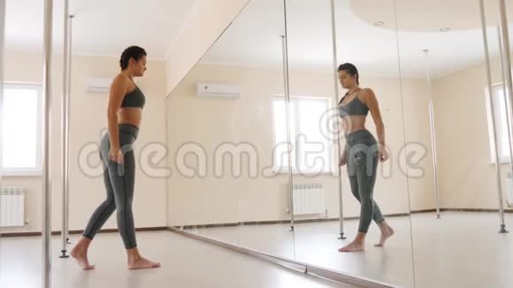 健身女性在镜子附近做伸展运动在室内运动的年轻女子视频的预览图
