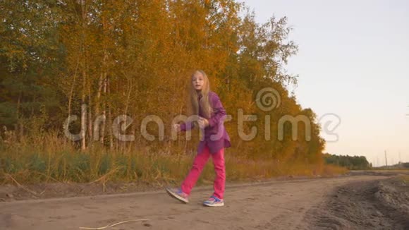白种人女孩在森林路上跳跃乡景金秋慢动作手持视频的预览图