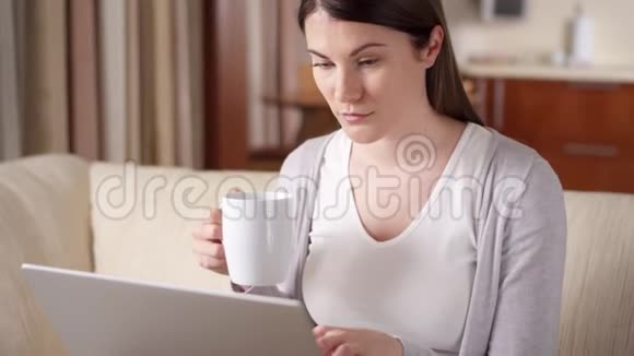 微笑的职业女性在家里用笔记本电脑工作喝咖啡家庭办公概念视频的预览图