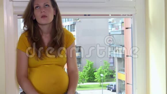 沮丧的孕妇打电话坐在窗台上大声喊叫视频的预览图