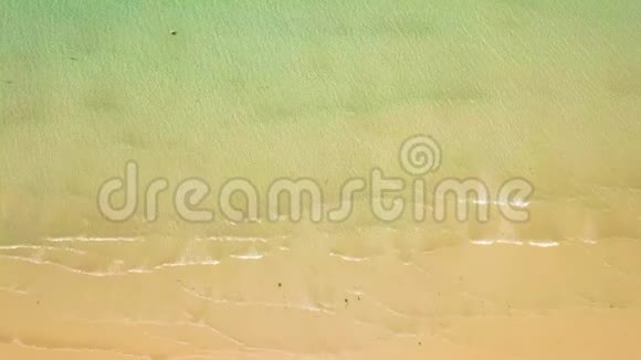 沙滩上的透明水海浪无人机景俯视清澈的海浪溅在沙质海岸上空的视频的预览图