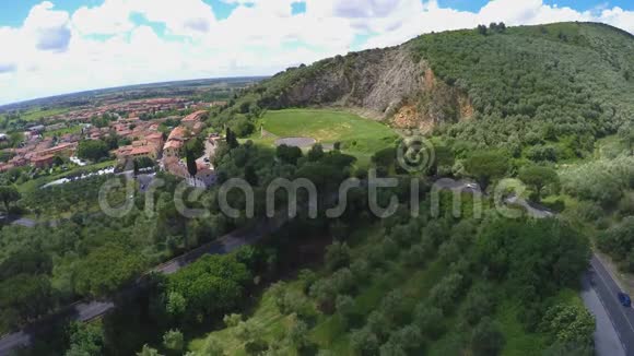 从蜿蜒的公路俯瞰美丽的意大利村庄坐落在绿草如茵的小山附近视频的预览图