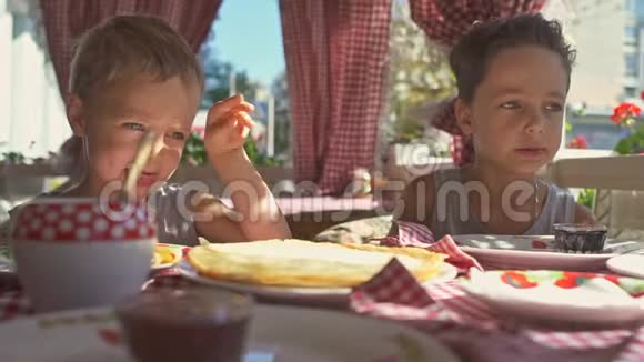两个男孩正在阳台上吃煎饼作为早餐视频的预览图