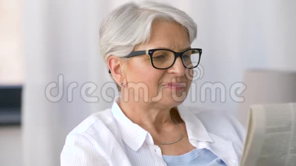 老年妇女在家看报纸的肖像视频的预览图